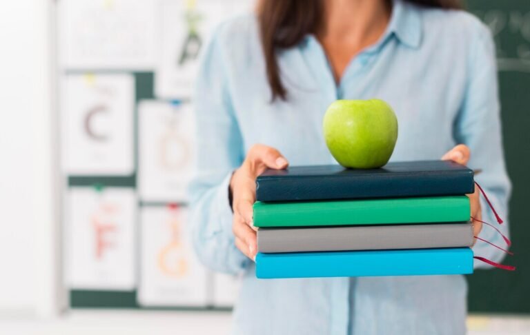 smiley-teacher-holding-bunch-books-apple_23-2148668531